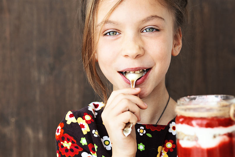 Young girl eating yogurt with a spoon